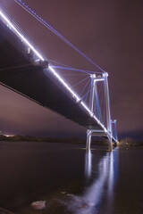 Beautiful view of the big bridge with bright illumination in the evening. Beautiful bridge across the river in the city