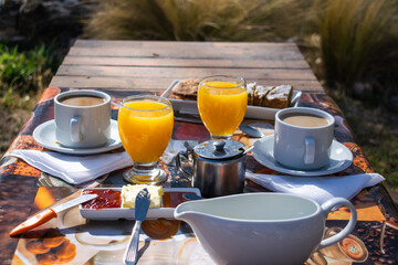 breakfast in the garden on a wooden table coffee milk orange juice and jams