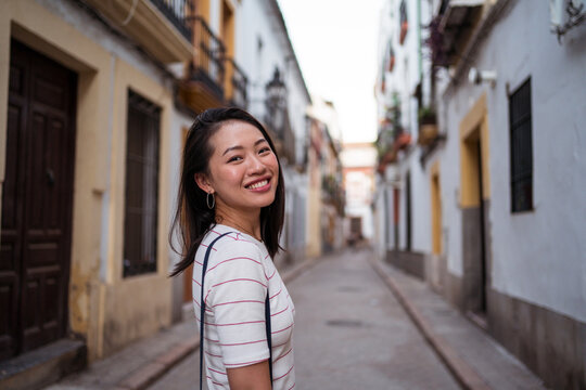 Positive Asian woman in narrow street
