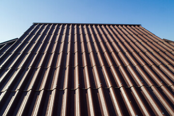 Modern roof. Roof covering. Roman profile. The roof of the house is covered with wavy brown tiles.