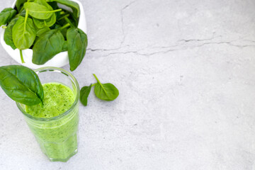 Top view of glasses filled with green smoothies on table with spinach leaves