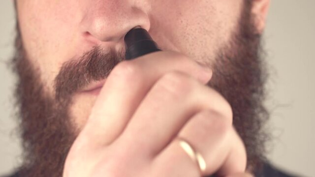Close up footage of man removing hair from nose with trimer.