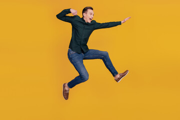 Fototapeta na wymiar Full body profile side photo of young crazy man look empty space kick jump up isolated over yellow color background