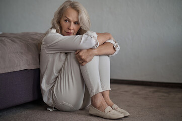 Fototapeta premium Beautiful low-spirited lady seated on the carpet looking away