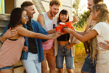 Multiracial friends drinking beverages during picnic by trailer