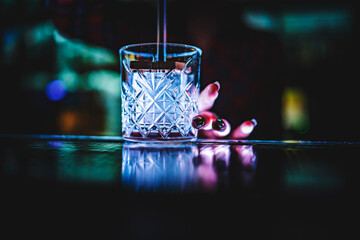 woman bartender stamping ice cube in the glass on the bar counter
