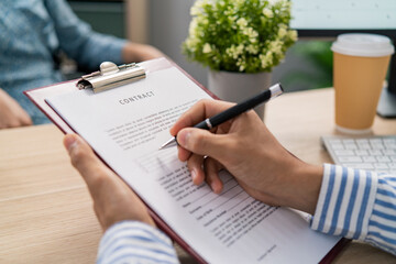 Man, employer sits at desk holds in hands employment contract for disabled woman sitting in wheelchair, boss signs document, hires girl