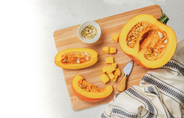 There is a half pumpkin and two cut pieces on a wooden board. Top view of the vegetable.