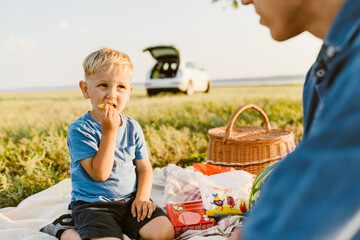 Young white father having picnic with his son on field