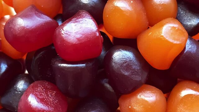 Close-up texture of red, orange and purple multivitamin gummies on white background. Healthy lifestyle concept