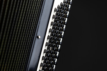 Part of a button accordion with showing black bass buttons on a dark background