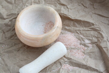 Natural stone spice mortar and pink Himalayan salt on craft paper background. Natural eco-friendly items and products.