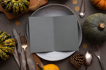 Autumn thanksgiving table setting with blank menu invite card surrounded by festive pumpkins