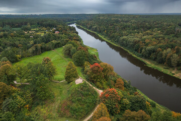 Fototapeta na wymiar Punia mound in Lithuania with green grass and autumn trees background, road to mountain