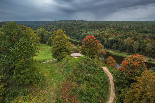 Punia mound in Lithuania with green grass and autumn trees background, road to mountain