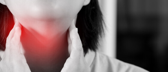 sore throat pain. Closeup of young woman sick holding her inflamed throat using hands to touch the ill neck in blue shirt on gray background. Medical and healthcare concept. Focus red on to show pain.