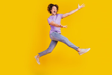 Fototapeta na wymiar Photo of nice inspired man jump raise hands empty space go wear casual jeans clothes on yellow background