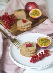 Tradtional French foie gras and toaster bread in a white plate  with redcurrant and passion fruit aside. To celebrate a new year's eve and festive.