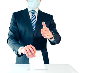 Elegant man in suit jacket and face mask putting ballot paper in voting box against white...