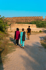 Three people walking in Rohtas Fort towards the well