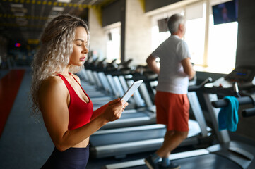 Old man on treadmill, female trainer with laptop