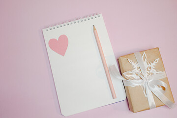 gift, white ribbon, snowflake, notepad, white sheet, pencil on pink background