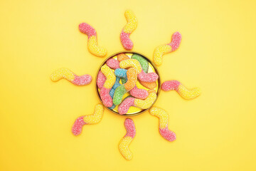 Sun made of gummy worms on yellow