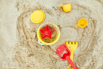 Fototapeta na wymiar Top view, flat lay of scattered plastic beach toys on sand background
