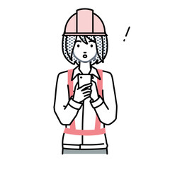 立ってスマートフォンを操作して何かに気づいて驚いた工事現場の女性