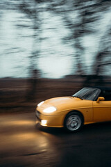 Fast moving yellow car cabriolet on the road 