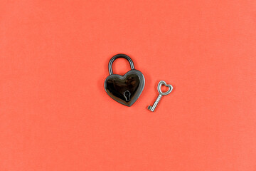 Hanging heart-shaped lock and key on red paper background