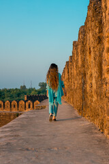 Back view of a girl in Pakistani dress walking in ancient Rohtas Fort
