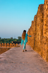 Back view of a girl in Pakistani dress walking in ancient Rohtas Fort
