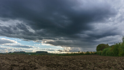 Rain and storm clouds over plowed agricultural field, Eifel, Germany