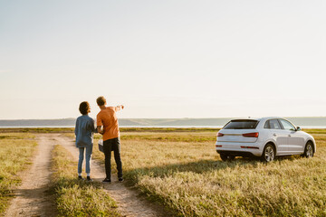 Multiracial couple hand pointing away on field during car trip © Drobot Dean