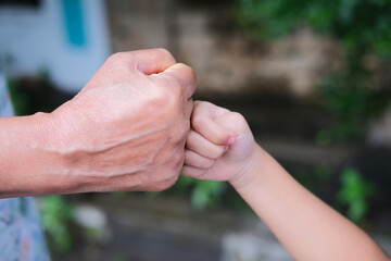 Elderly woman hand doing fist bump with little kid hand