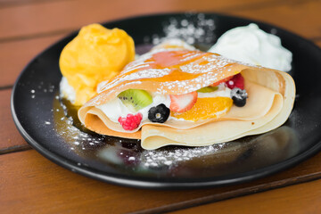 Delicious tasty homemade crepes or pancakes with raspberries, melon, blueberries and icecream.