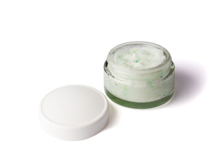 Texture cosmetic scrub for face and body in glass jar with white cap. Body scrub with green crystals. Isolated on white.