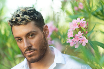 Shallow focus shot of a young attractive Caucasian guy from Italy in an oleander garden