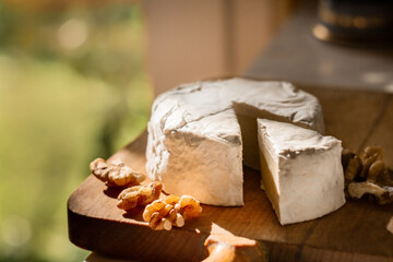 Brie cheese or camembert on cheese platter with walnuts. Closeup view, selective focus