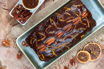 Homemade ginger loaf cake with plum marmalade, pecan nuts and chocolate ganache
