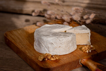 Camembert cheese, walnuts, sacking on cutting board, cut slice Camembert cheese, wooden background ,selective focus