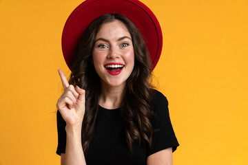 White young woman in red hat smiling while pointing finger upward