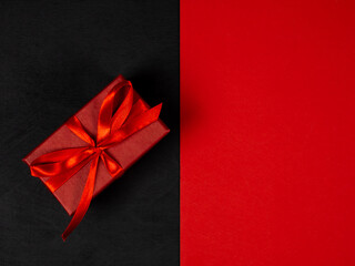 Gift box with a red bow. Christmas composition. Black and red background. Christmas, New Year concept.