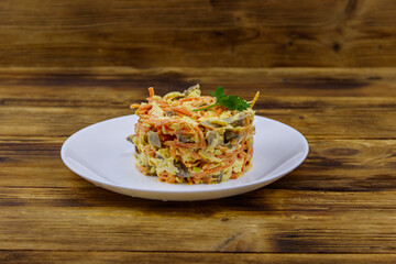 Tasty salad with pork heart, carrot in Korean, onion,  cheese and mayonnaise on wooden table