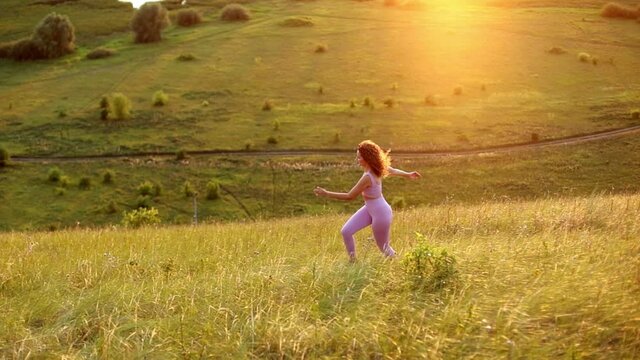 Young woman exercising outdoors against the backdrop of a beautiful sunset. When the sun goes down in summer, healthy running and outdoor exercise concept