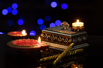 Handcrafted Eco Friendly Clay Diya Deep Dia Glowing lamps on a reflective base with gift box and golden candles sticks for Hindu festival Laxmi pooja (Diwali),with glittering bokeh