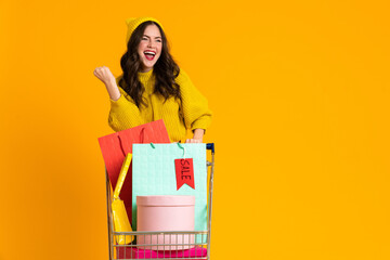 White woman making winner gesture while posing with shopping cart © Drobot Dean