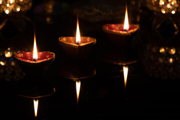 Glowing Eco friendly Clay Diya Deep Dia lamps arranged or placed in a sequence pattern on a reflective base for Hindu festival Laxmi poojan (Diwali), with glittering golden bokeh