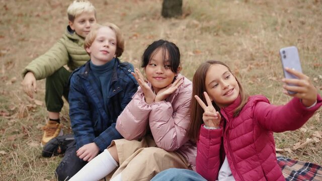 Happy multinational group of children making selfie on phone at picnic time